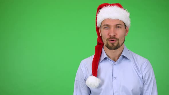 A Young Handsome Man in a Christmas Hat Talks To the Camera with a Smile - Green Screen Studio