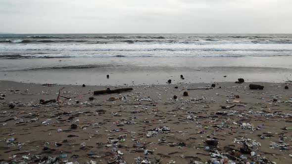 Slow motion tracking shot at the beach, plastic pollution washing out from the ocean at Bali, Indone