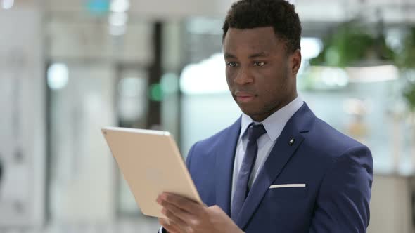 Attractive African Businessman Using Tablet in Modern Office