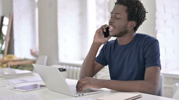 Young African Man Talking on Smartphone in Office