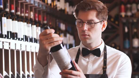 Sommelier Presenting Bottle of Red Wine To Customer in a Wine Store