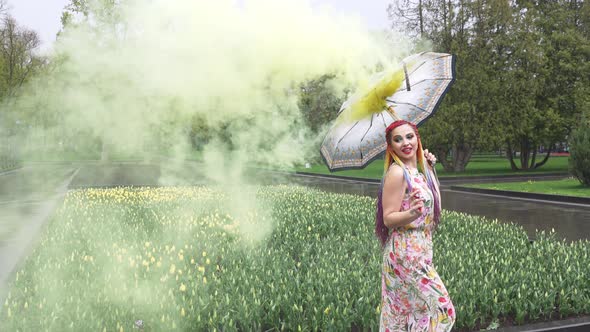 Girl with African Braids and Makeup in Spring Dress is Dancing in the Rain with Umbrella in Yellow