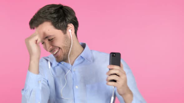 Dancing Young Man Listening Music on Smartphone on Pink Background