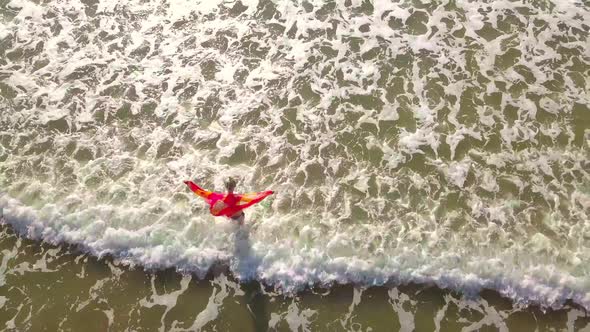 shooting from a drone, a woman enters the sea, and rejoices. happiness.