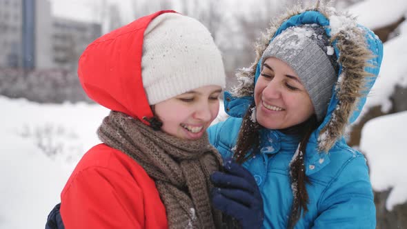 Mother and Daughter Teenager Cuddling and Having Fun in the Winter in the Snow