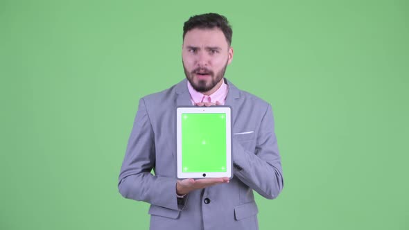 Happy Young Bearded Businessman Showing Digital Tablet and Looking Surprised