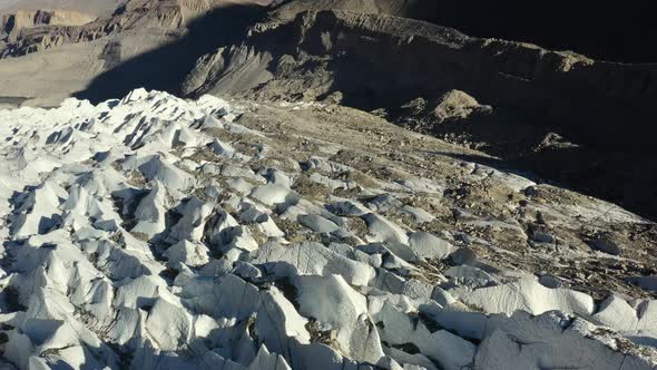 aerial drone flying over the crevasses of Passu Glacier in Hunza Pakistan along with dirt and rock m