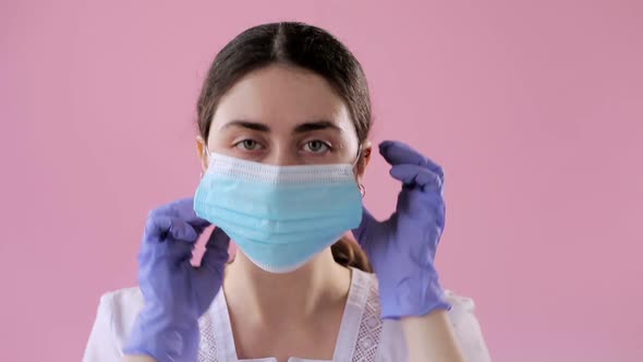 Portrait of a Young Woman Doctor in Medical Gloves Wearing a Mask to Protect Against the Virus