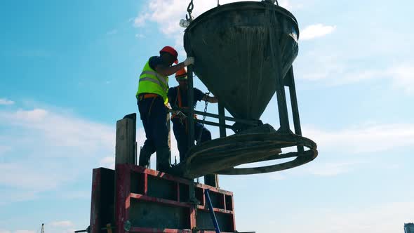 Builders Work with Cement Container, Attaching It To Crane Ropes alt