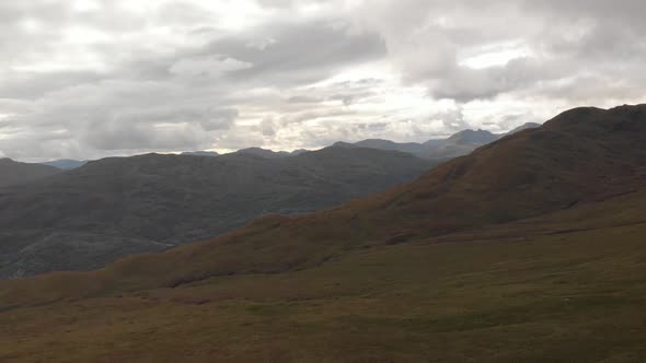 Panoramic drone shot of mountains with green grass in loch lomond national park in scotland. Cloudy