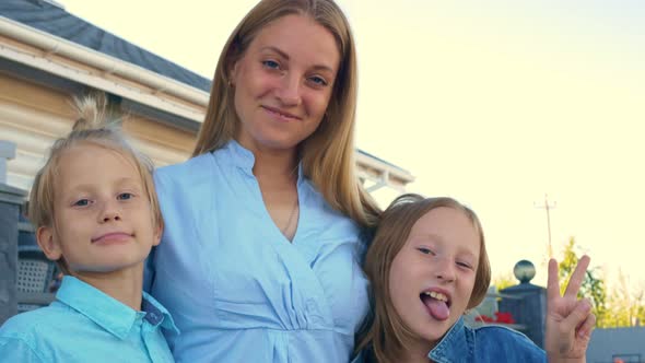 A Beautiful Mother and Children are Posing in Front of the Camera the Children are Making Faces and