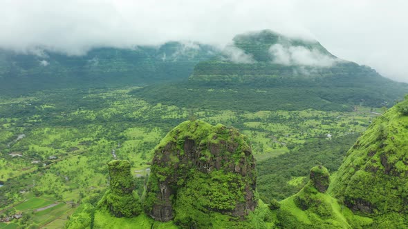 Flying over the green cliffs to reveal the rice paddies and village on the plains on the other side