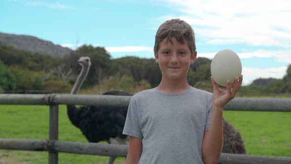 Boy Holding Ostrich Egg at Ostrich Farm