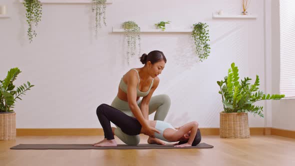 Asian yoga trainer teaches little girl doing back bend yoga in home studio.Bridge pose strengthen ba