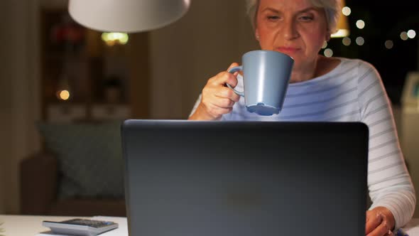 Senior Woman with Laptop Drinking Coffee at Home