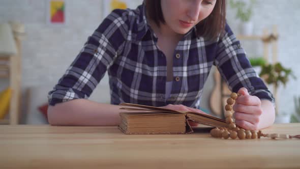 Close Up of a Young Woman with a Rosary in Her Hands Reading the Bible