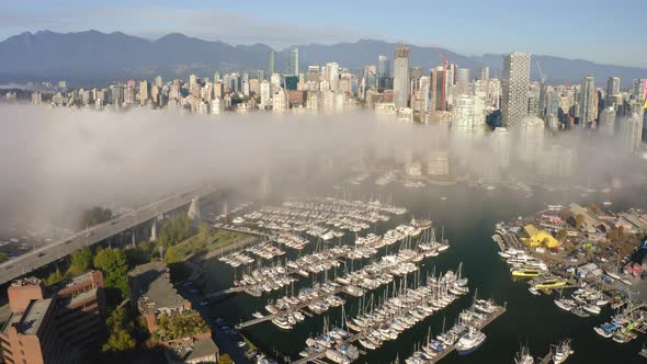 Aerial flying away from the scenic downtown Vancouver skyline on a misty morning.