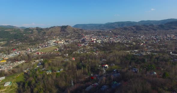 Drone shot of a beautiful village with beautiful houses, trees, hills and blue sky.