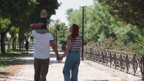 Young Family on a Walk in Summer Day