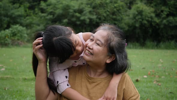 Slow motion of Happy grandmother with granddaughter playing in the park