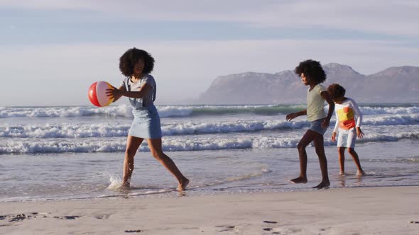 African american mother and her children playing with a ball on the beach