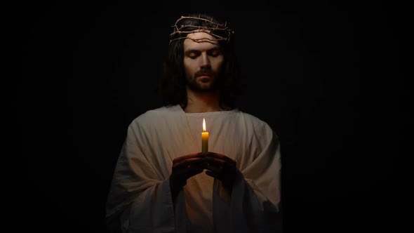 Jesus Christ in Crown of Thorns Holding Candle and Praying for God Blessing Hope