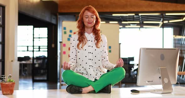 Businesswoman meditating in lotus pose