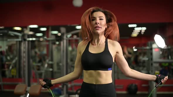 Young woman warming up before training in the gym, jumping rope