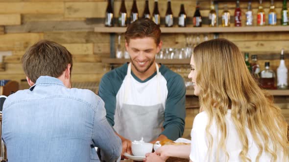 Waiter serving cup of coffee to customers at counter 4k