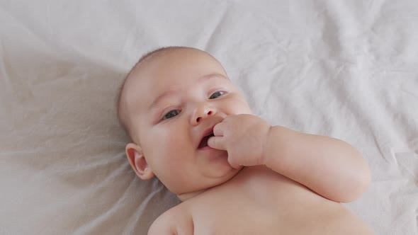 Little Baby with Finger in Mouth on a Bed.