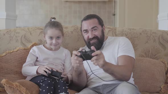 Portrait Cute Small Daughter with Her Funny Father Playing Video Games on Tv with Great Emotions in