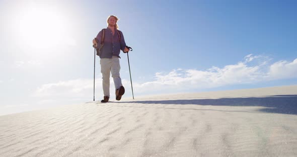 Man with hiking pole walking in the desert 