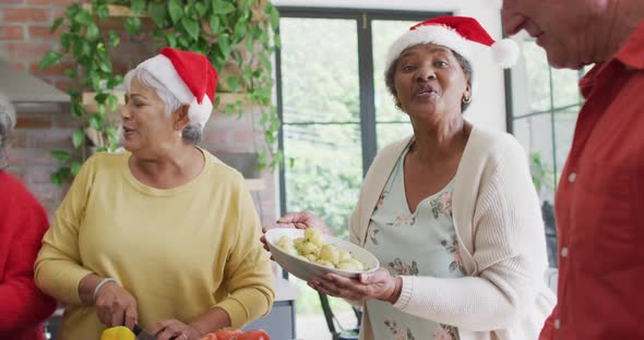 Group of happy diverse senior friends cooking together in kitchen at christmas time