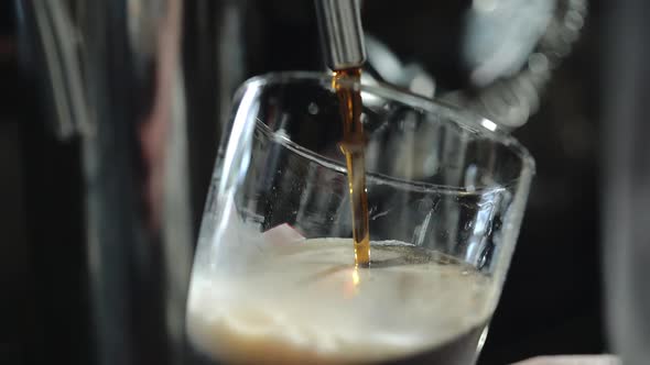 Bartender pours a dark beer in glass. Close-up.