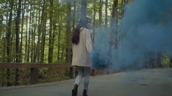 Woman with blue smoking torch in nature