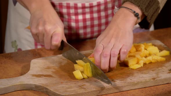 Cutting zucchini on a wooden cutting board in the kitchen by a young woman