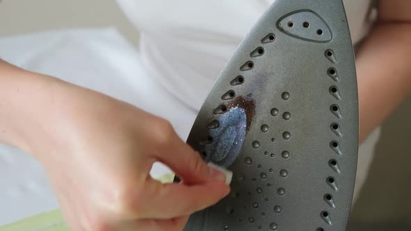 A Woman Cleans the Surface of the Iron with a Cleaning Pencil