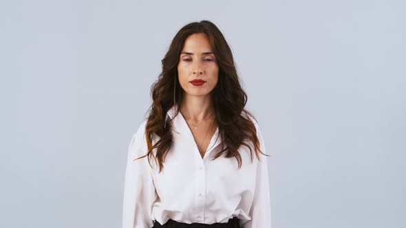 Feminine Brunette Woman in White Shirt is Saying Stop and Showing Stop Sign By Her Outstretched Palm