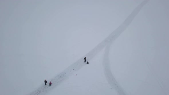 Birds eye view of people having fun on frozen lake during their hike in spite of cloudy and overcast