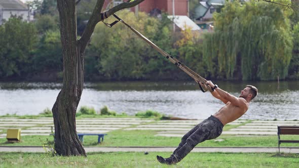 Training in open air. Young man working out by the lake in city park