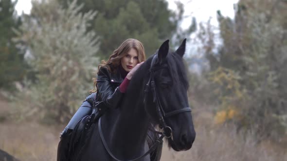 Beautiful Young Woman Sitting Astride Hugs a Horse and Posing Outdoors