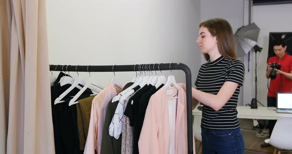 Female stylish selecting apparel from clothes rack