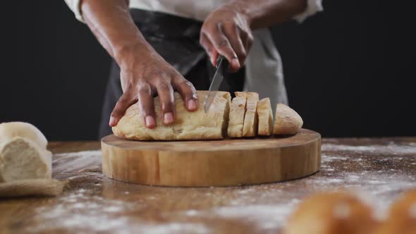 Video of cook cuts the loaf of bread on black background