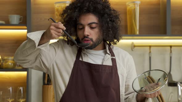 Egyptian Man Chef Tastes Cooked Soup From Ladle in Kitchen