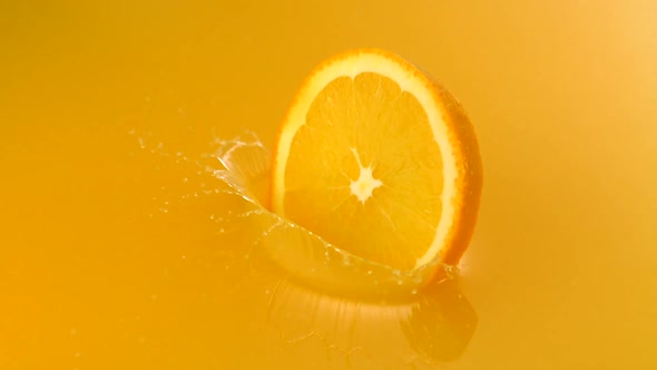 Sliced orange falling into orange juice, Slow Motion