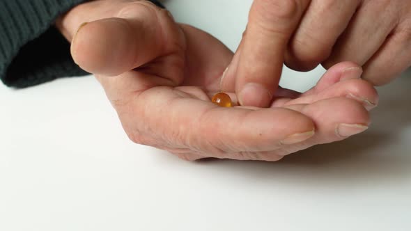 The benefits of vitamins omega 3 fish oil, an elderly man takes vitamins holding in his hand