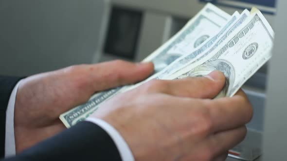 Business Person Counting Dollars Near ATM and Putting Money in Wallet, Banking