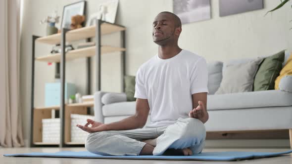 Young African Man Meditating on Yoga Mat at Home