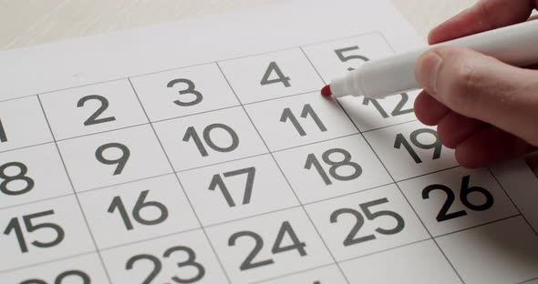 Man's Hand Write Down the 23Th Day on the Paper Calendar Using a Red Pen