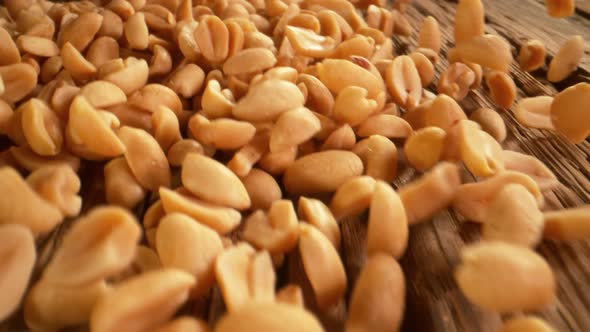 Super Slow Motion Detail Shot of Peanuts Rolling Towards on Wooden Background at 1000Fps